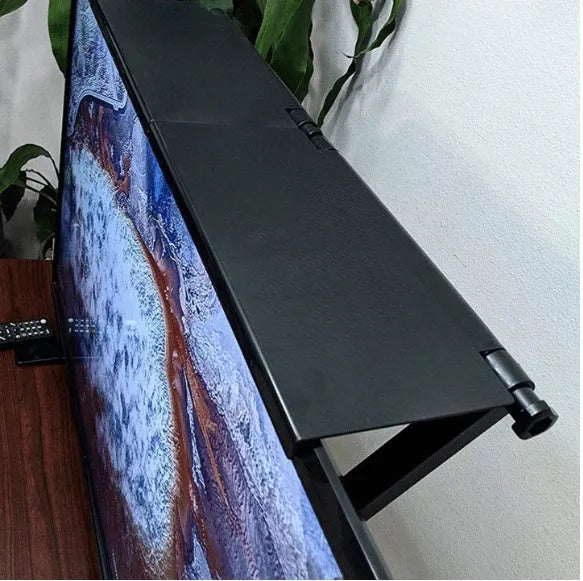 Black adjustable screen top shelf mounted on a monitor holding a streaming device and remote