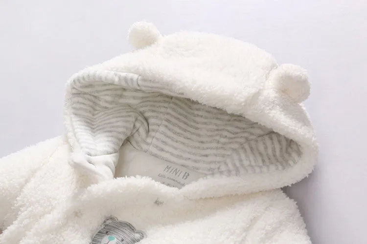 Baby wearing white cotton padded romper with lamb design and feet covers