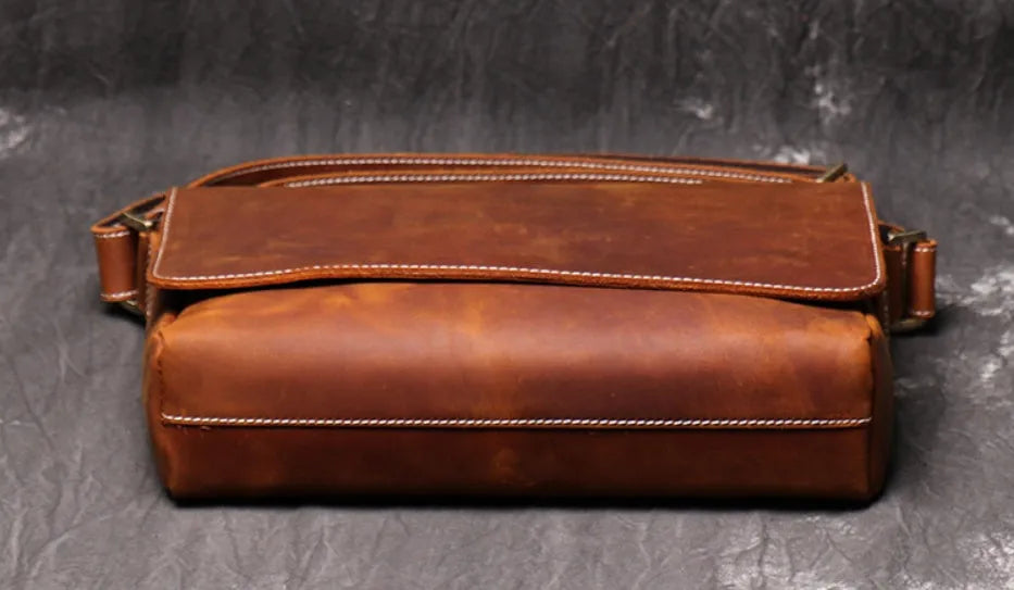 Vintage brown cowhide men's messenger bag showing front flap and adjustable shoulder strap