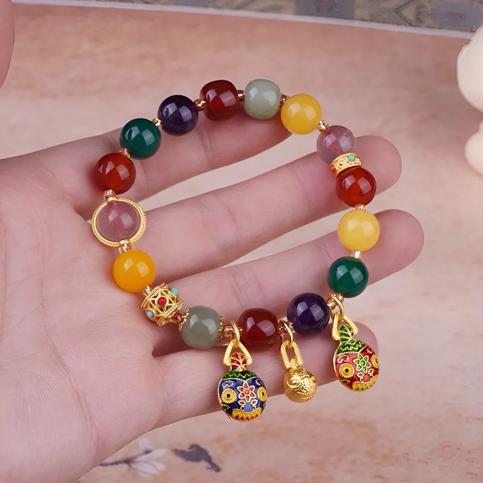 Close-up of a bracelet with a hand-woven gold beast charm and large brown agate beads.