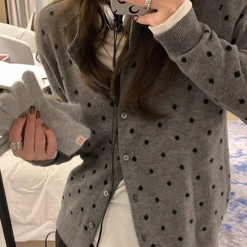 Grey dot patterned women's knitted cardigan with crochet flower details on a hanger.