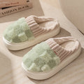 Plaid pattern women's plush slippers with round toe and flat heel on a coloured background.
