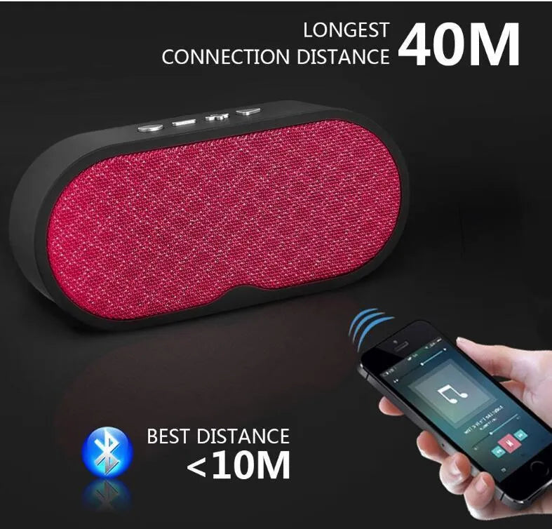 Grey portable Bluetooth speaker with subwoofer, HD microphone, TF card slot and USB port on a table.