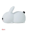 White silicone rabbit night light with warm and white LED glow on a wooden bedside table