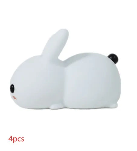White silicone rabbit night light with warm and white LED glow on a wooden bedside table