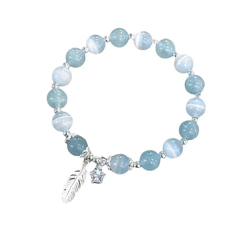 Korean style blue crystal bracelet with white lettering and a star charm on a wrist.