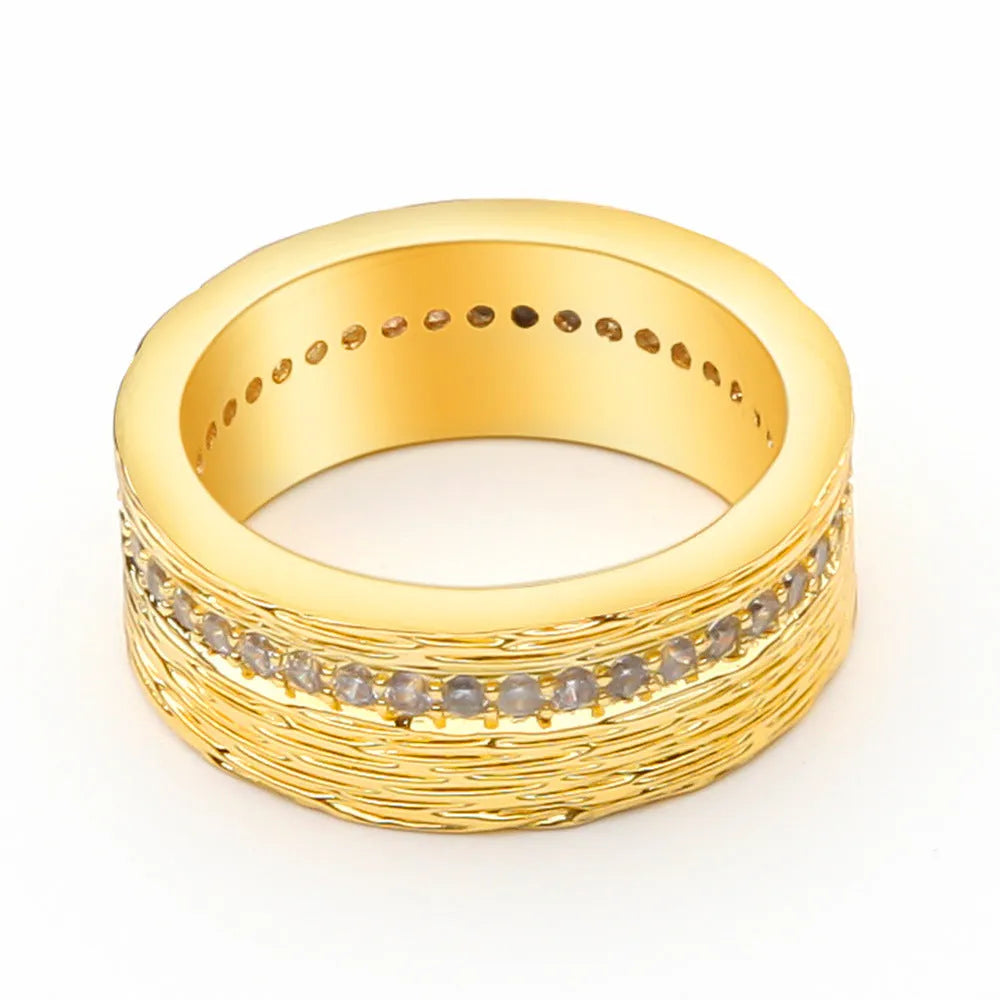 Geometric gold-colour copper ring with zircon stone on a grey background.