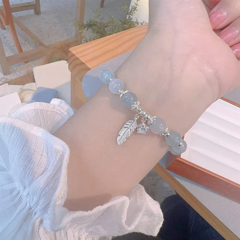Korean style blue crystal bracelet with white lettering and a star charm on a wrist.