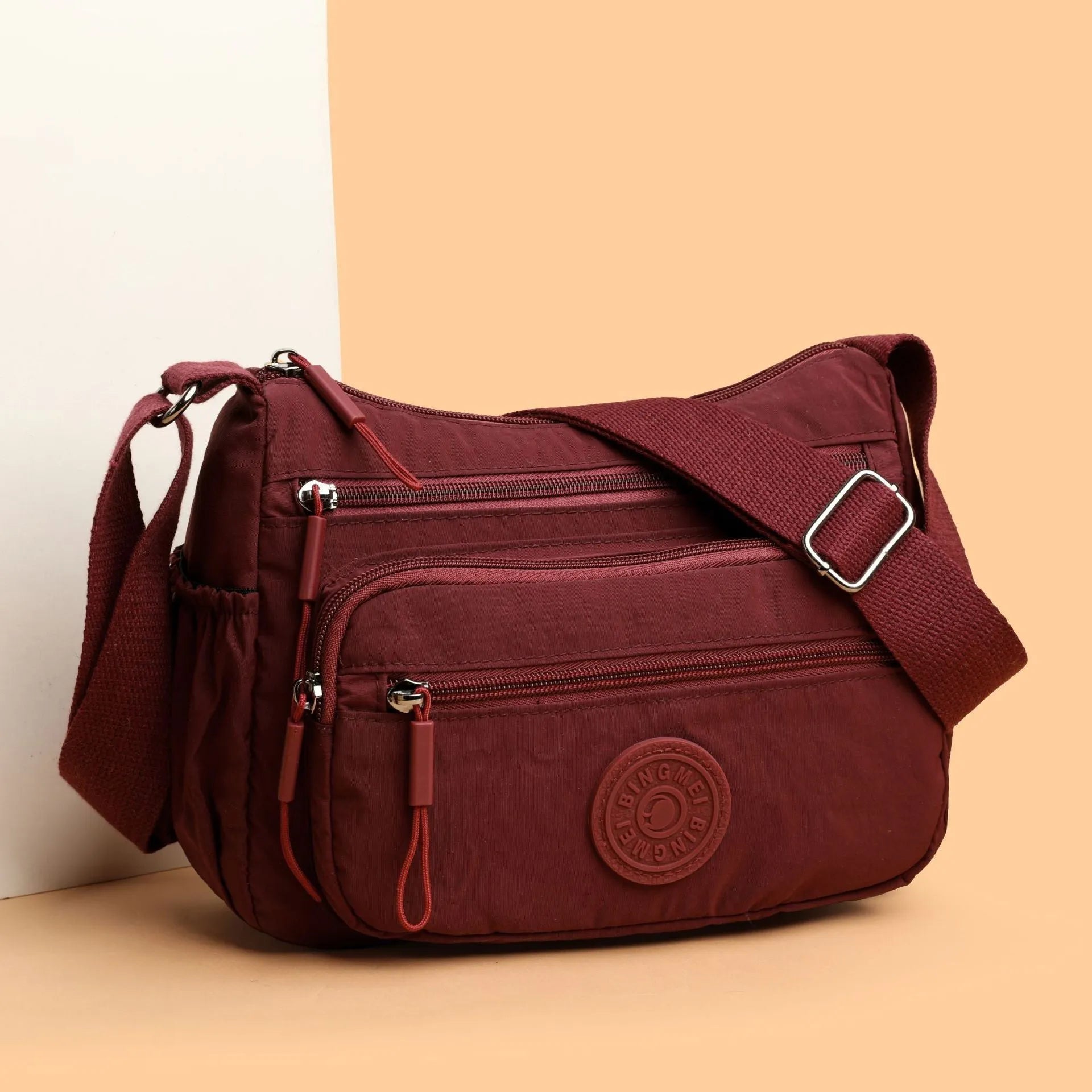 Soft grey nylon crossbody bag with an external pocket and adjustable shoulder strap.