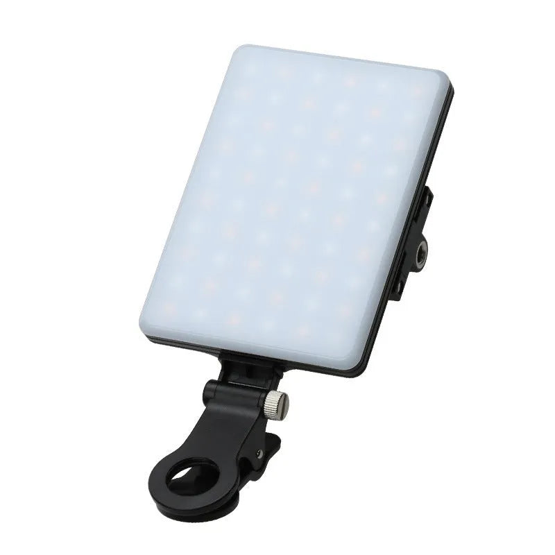 White portable LED fill light clipped to mobile phone with adjustment knob visible