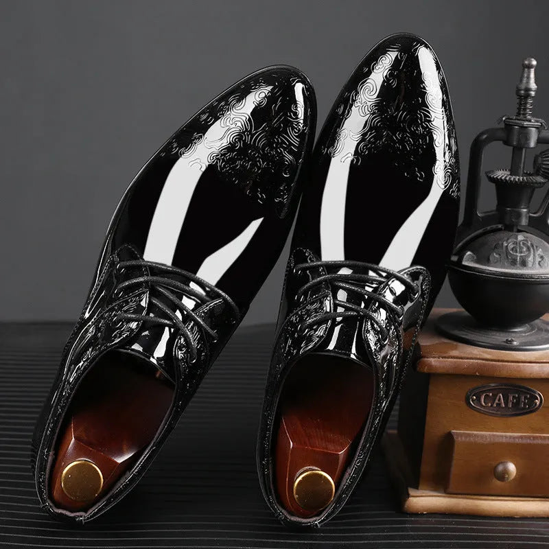 Glossy black men's business formal shoes with patent finish, pointed toe, and carved detail on a neutral background