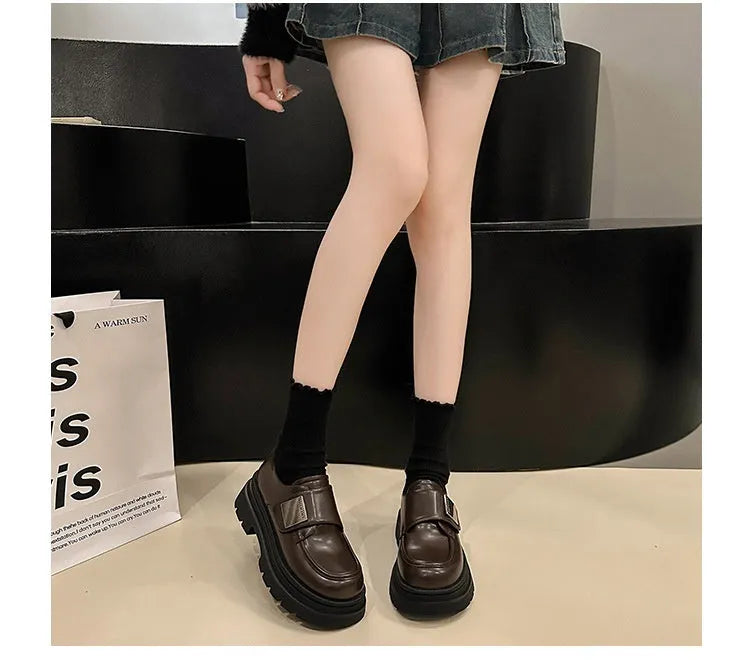 Women's black chunky square heel shoes with cross strap and round toe on a neutral background