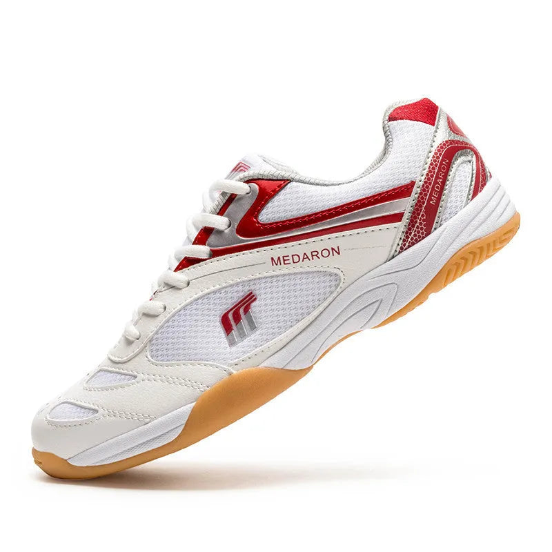 White and blue table tennis shoes with mesh panels and rubber sole on a court surface.