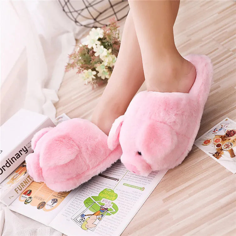 Pink pig-shaped plush floor slippers with soft filling on a plain background.