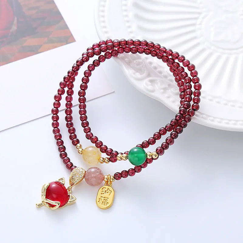 Purplish red garnet fox charm on an adjustable rope bracelet for women.