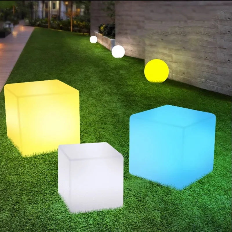 A modern, square white LED cube light functioning as a waterproof outdoor stool.