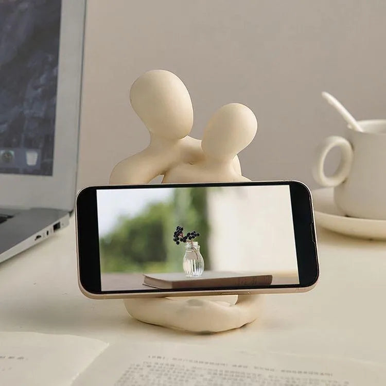 Modern minimalist loving couple resin statue in gold or milky white on a wooden surface.