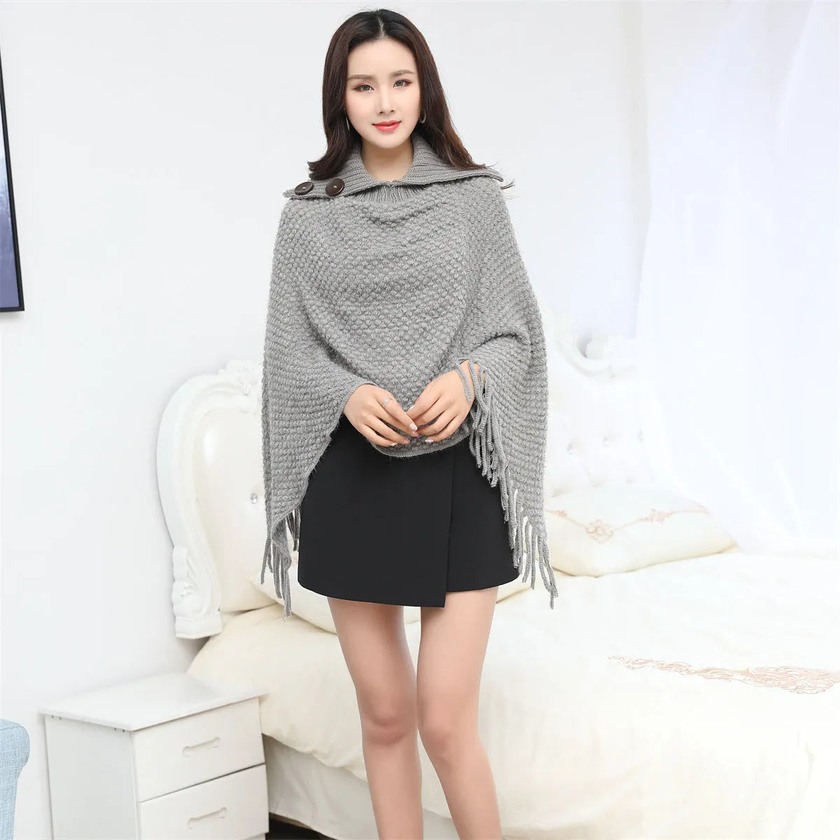 Dot-patterned acrylic knitted shawl cloak in apricot colour, laid flat.