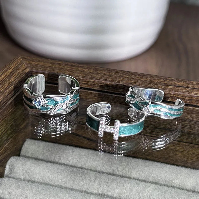 Mint green and copper asterism ring with asymmetric folding design on a hand.