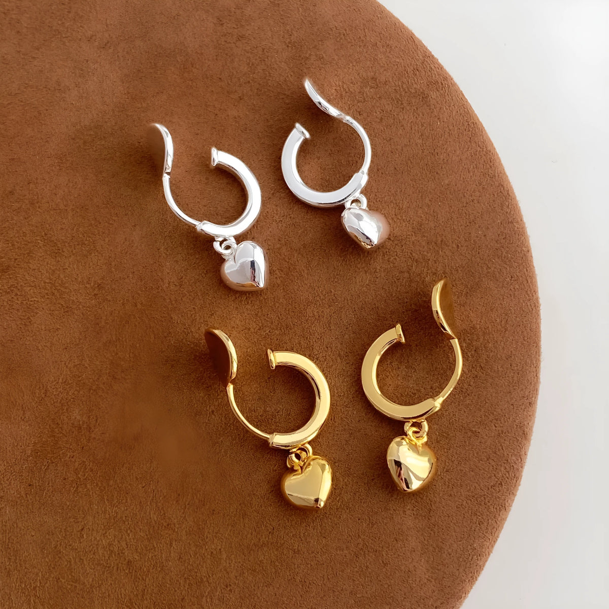 Pair of copper heart-shaped C-style earrings in gold electroplated finish on white background