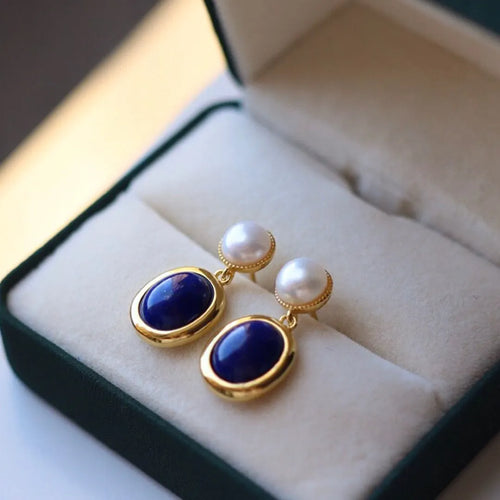 A pair of simple sterling silver stud earrings with a blue lapis lazuli pearl drop.