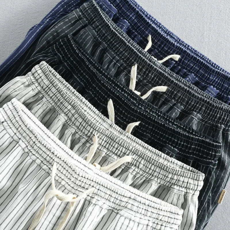 Man wearing striped light grey casual cotton shorts with a straight leg and elastic waistband.