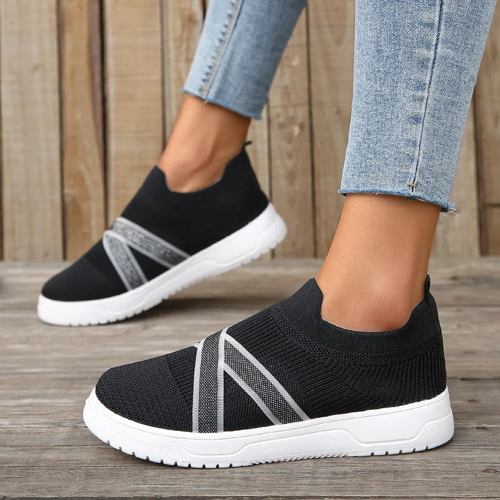 Black women's flat shoes with flyknit mesh upper, round toe, tassel detail, and flat rubber sole.