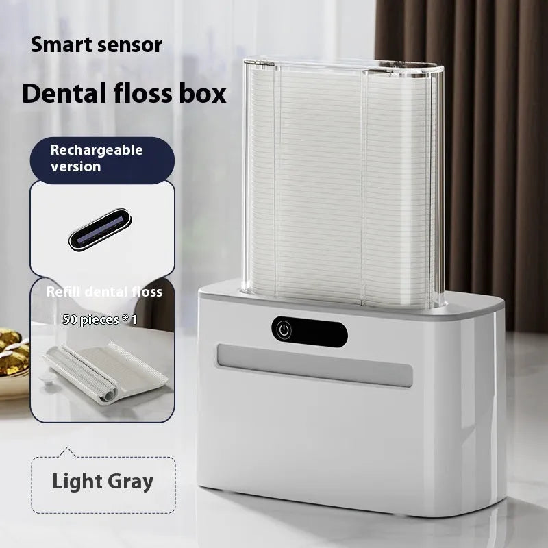 Dark gray automatic electric dental floss box with pop-up floss dispenser on a bathroom counter.