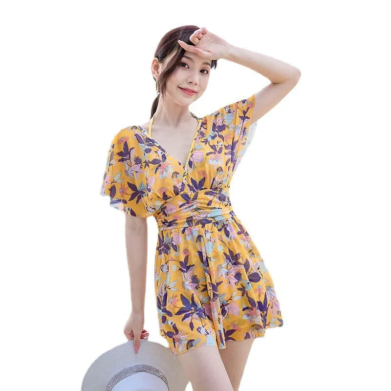 Yellow women's one-piece swimsuit with a floral pattern, shown on a hanger.