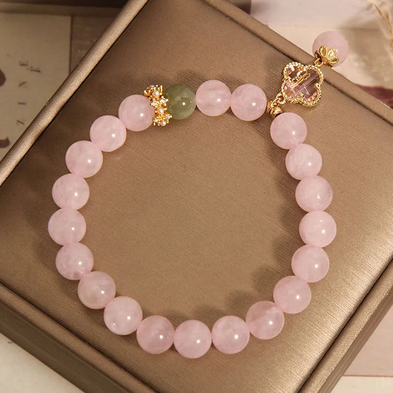 Pink crystal bracelet with four-leaf clover pendant and rhinestone details on women's wrist