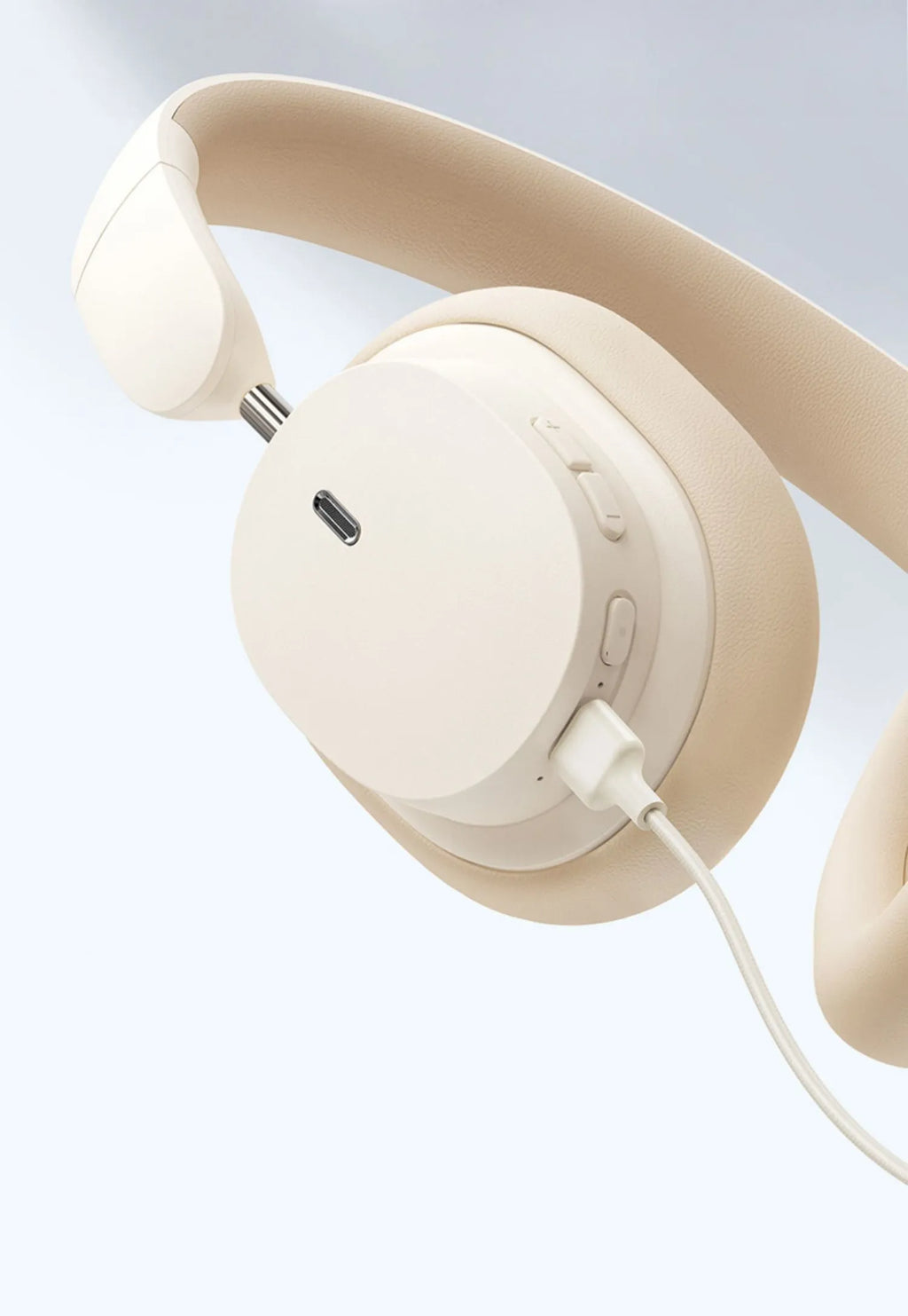 Beige and grey Bluetooth over-ear headphones with a Type-C charging cable on a table.