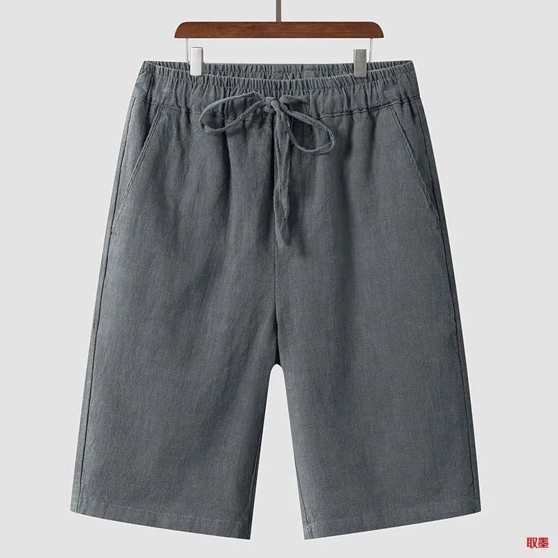 Men's beige linen shorts with loose cropped leg and elasticated waistband on a neutral background.