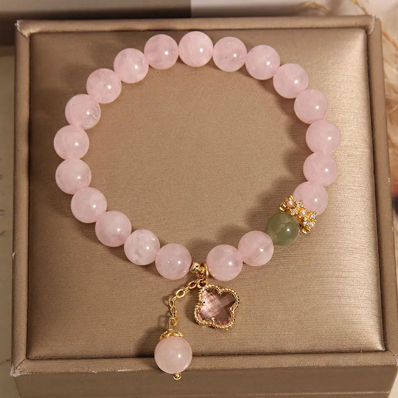 Pink crystal bracelet with four-leaf clover pendant and rhinestone details on women's wrist