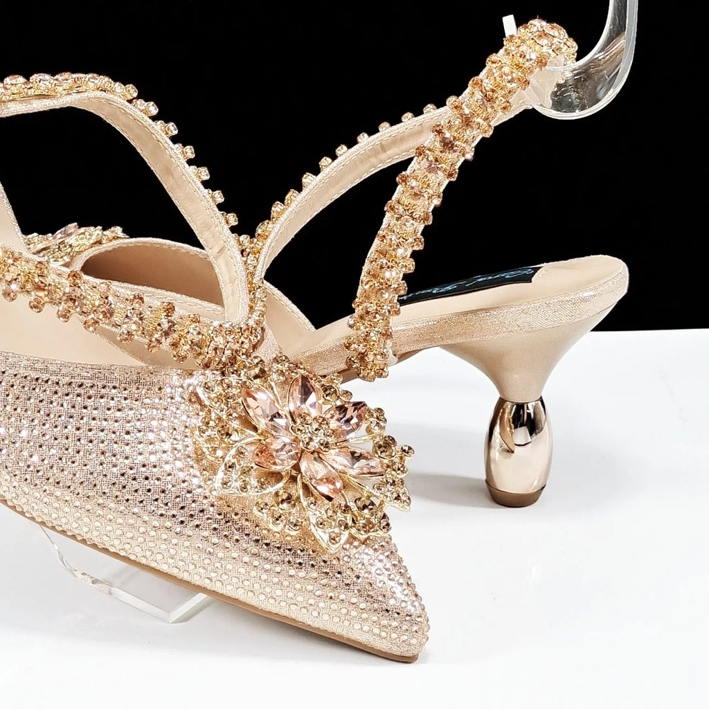 Women's black high heel and matching clutch bag set with floral decoration and rhinestones.