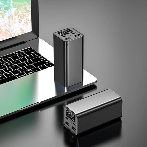 A black metal 65W laptop power bank with 20000mAh capacity, showing size compared to a hand.