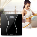 Black electronic digital bathroom scale on a hard floor, showing a weight reading on its display.