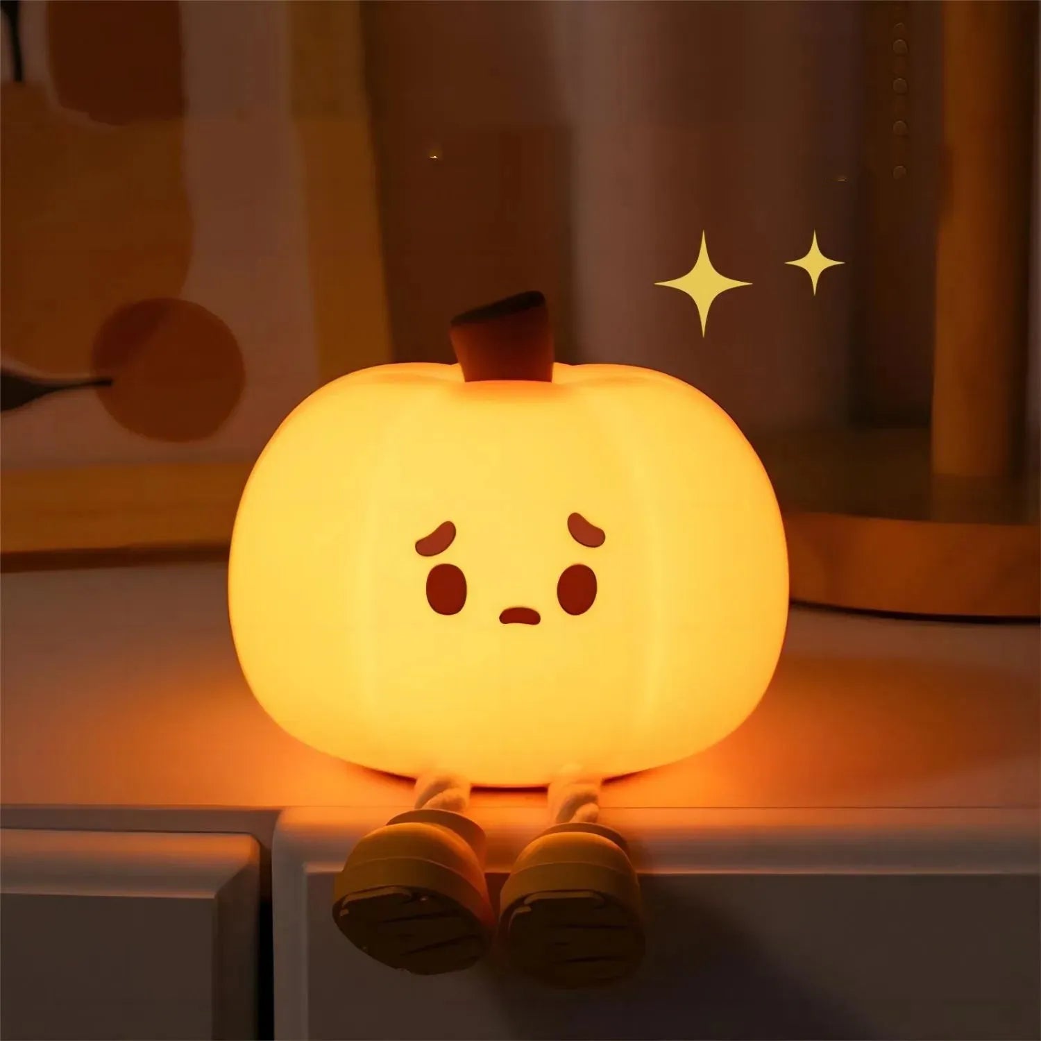 Soft orange silicone pumpkin-shaped night light with a warm glow on a bedside table.
