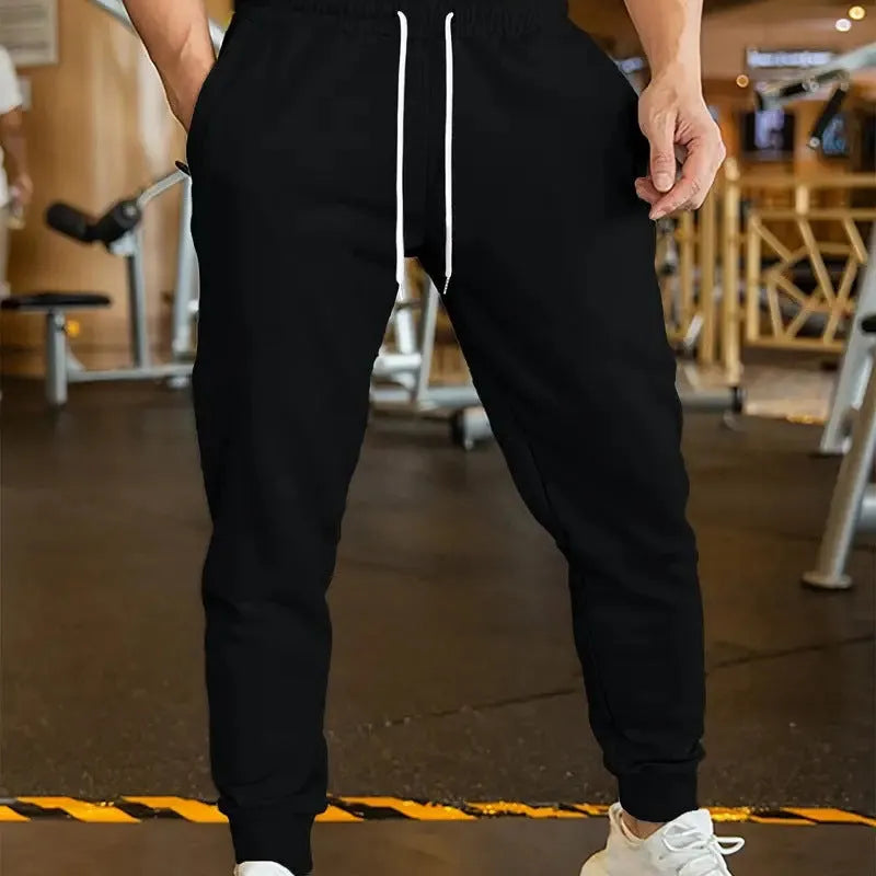 Man wearing grey loose-fit linen-style leisure trousers with an elastic drawstring waistband.
