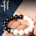 Black and white taiji bracelet with woven obsidian beads showing six word mantra and bagua symbol