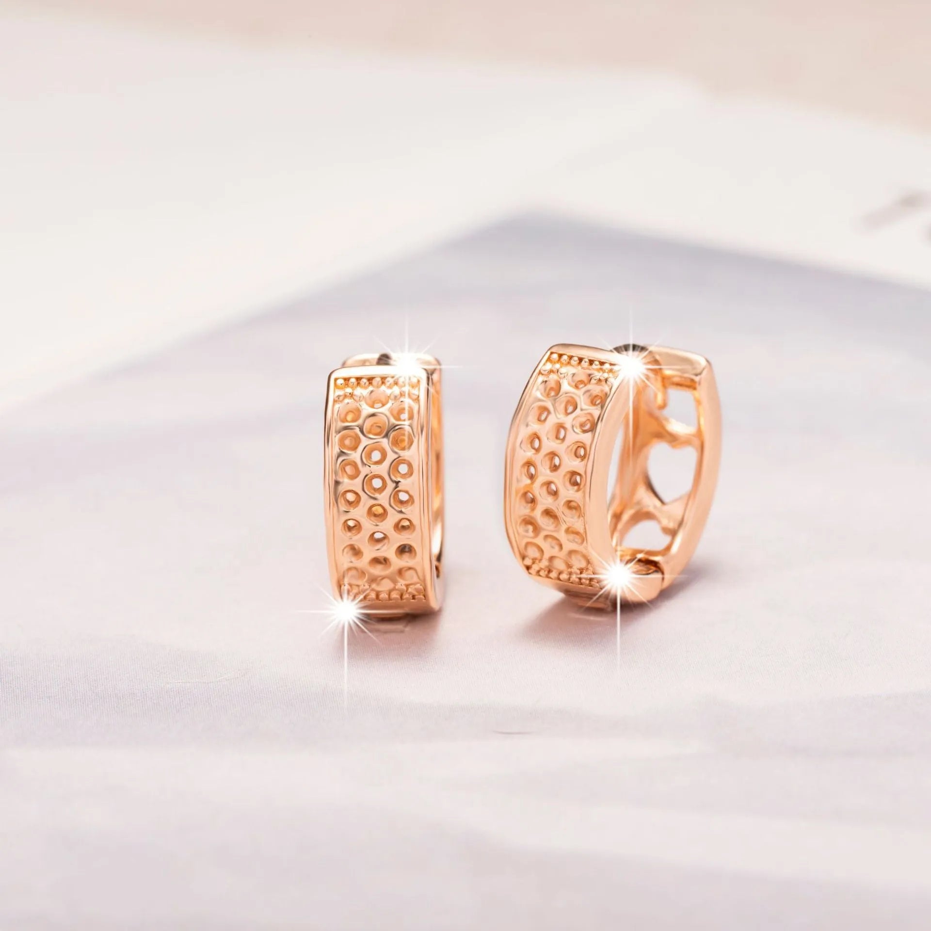 Rose gold hollowed-out stainless steel earrings showing three heart shapes in a circular design.