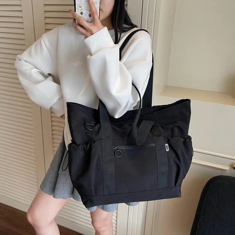 Lightweight Oxford cloth travel bag for women in grey, shown with a letter-pattern lining and holding a yoga mat.