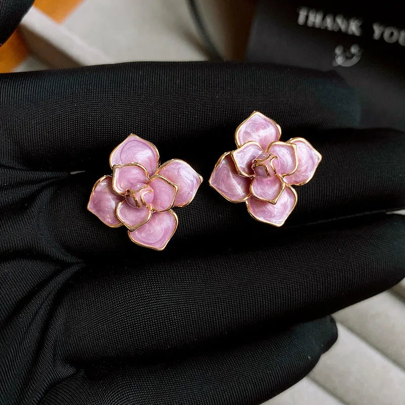 Close-up of a pair of gold plated flower stud earrings with a purple oil-spot glaze finish.