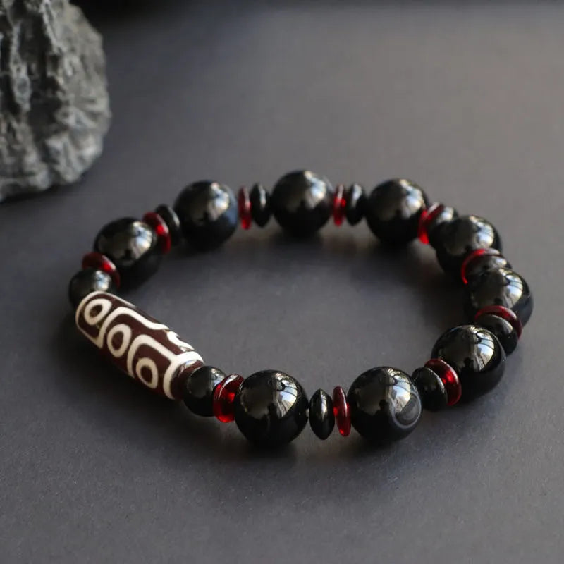 Black agate dzi bead bracelet with hand-woven geometry beads on a wrist.