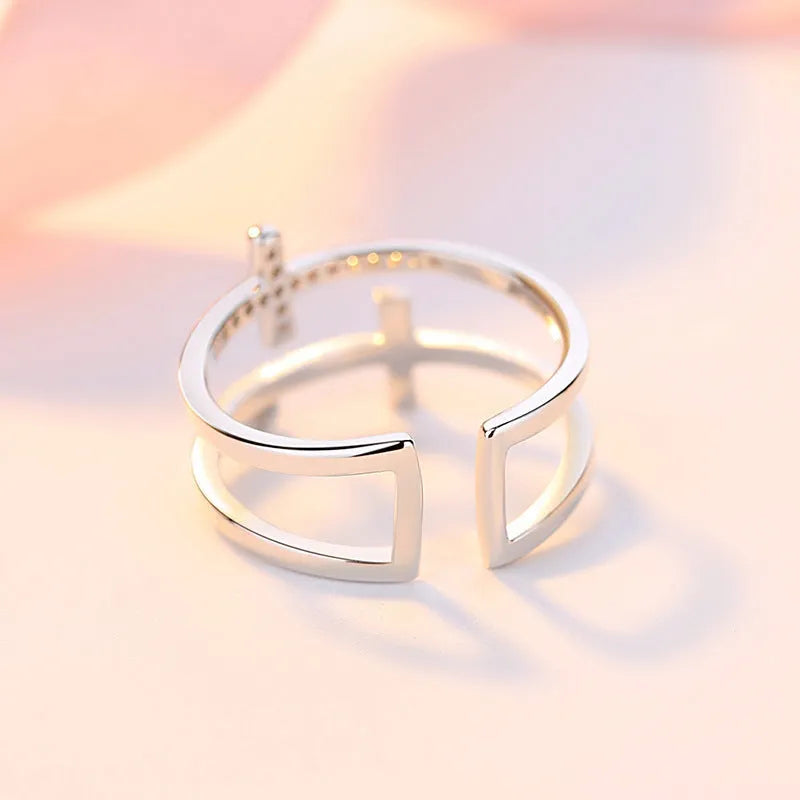 Adjustable double cross geometric ring with zircon stones in a white gold colour finish.