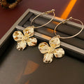 Geometric metal flower earrings with silver needle detail in gold or silver electroplated finish.