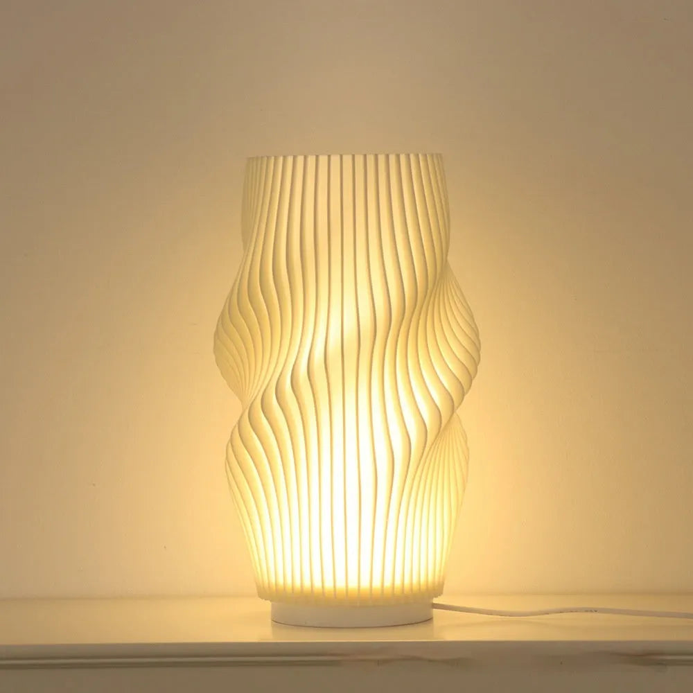 3D printed cylindrical vase night lamp with glass shade in wood colour finish on a bedside table
