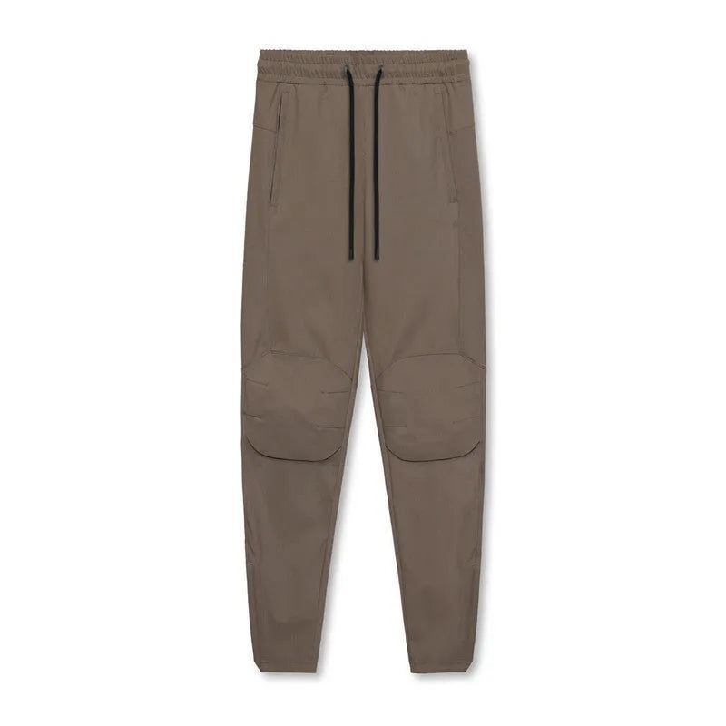 Man wearing dark grey loose-fit ankle-tied fitness trousers made of quick-drying polyester.