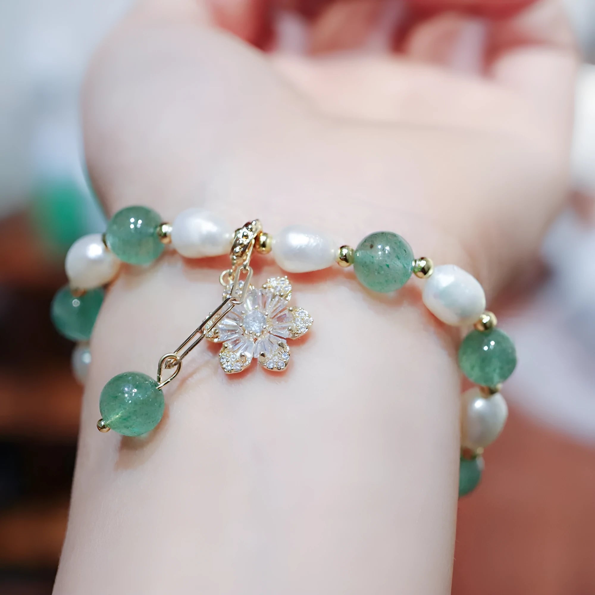 Green geometric strawberry freshwater pearl bracelet with small flower charm and Chinese knot design.