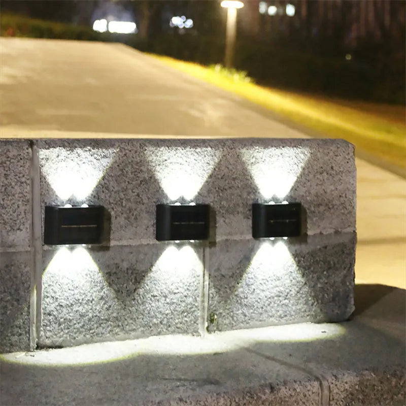 Black solar outdoor garden wall light with up and down glowing effect on a brick wall at night