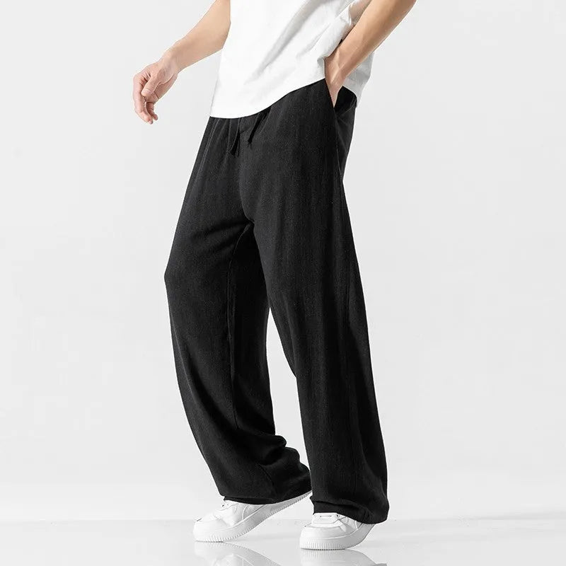 Man wearing beige cropped straight-leg linen trousers with a drawstring waist.